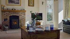 Ein gemütliches Wohnzimmer mit Kamin, Couchtisch und Fernseher.
