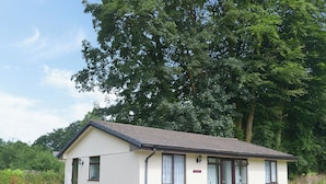 A small, single-story building with a pitched roof, a door, and windows. - 3 bedroom accommodation in Liskeard (Liskeard)