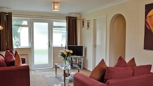 A living room with a sofa, a coffee table, and a television. - 3 bedroom accommodation in Liskeard (Liskeard)