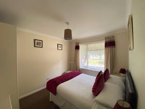 A bedroom with a bed, a window with curtains, and a ceiling light. - 2 bedroom accommodation in Liskeard (Liskeard)