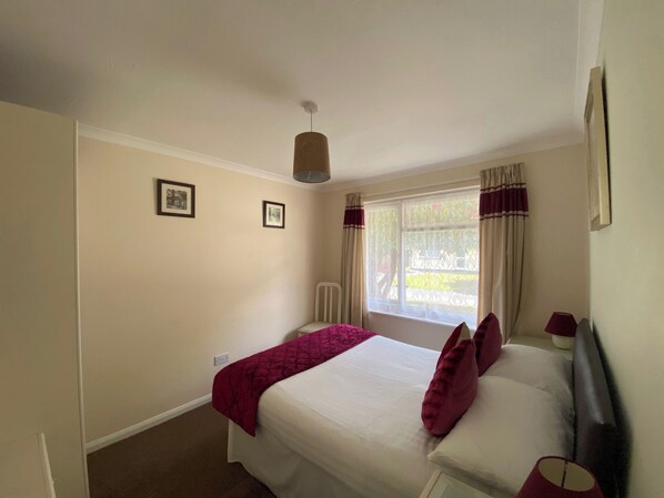 A bedroom with a bed, a window with curtains, and a ceiling light. - 2 bedroom accommodation in Liskeard (Liskeard)