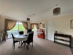 A spacious room with a dining table, chairs, a sofa, and a bed. - 2 bedroom accommodation in Liskeard (Liskeard)