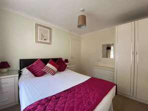 A neatly arranged bedroom with a bed, bedside tables, a wardrobe, and a mirror. - 2 bedroom accommodation in Liskeard (Liskeard)