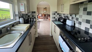 A narrow kitchen with a window, a sink, a toaster, and a stove. - 2 bedroom accommodation in Liskeard (Liskeard)