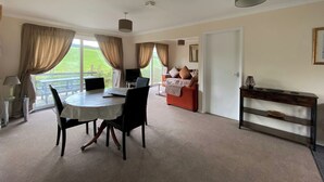 A spacious room with a dining table, chairs, a sofa, and a bed. - 2 bedroom accommodation in Liskeard (Liskeard)