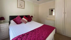 A neatly arranged bedroom with a bed, bedside tables, a wardrobe, and a mirror. - 2 bedroom accommodation in Liskeard (Liskeard)