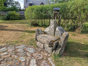 Un banco de piedra con un comedero para pájaros en un jardín.