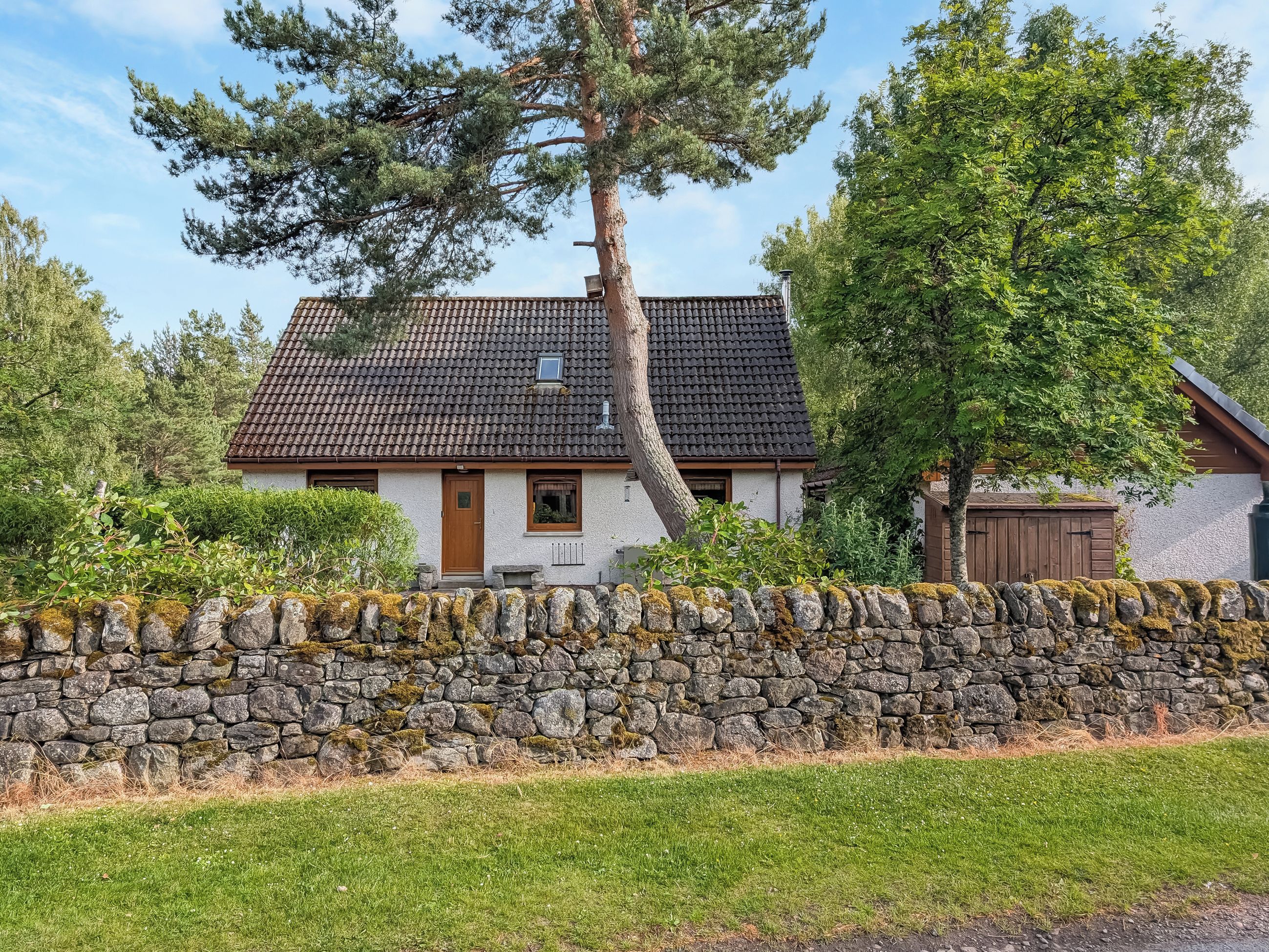A traditional stone-walled house with a tiled roof, a wooden door, and a small window.