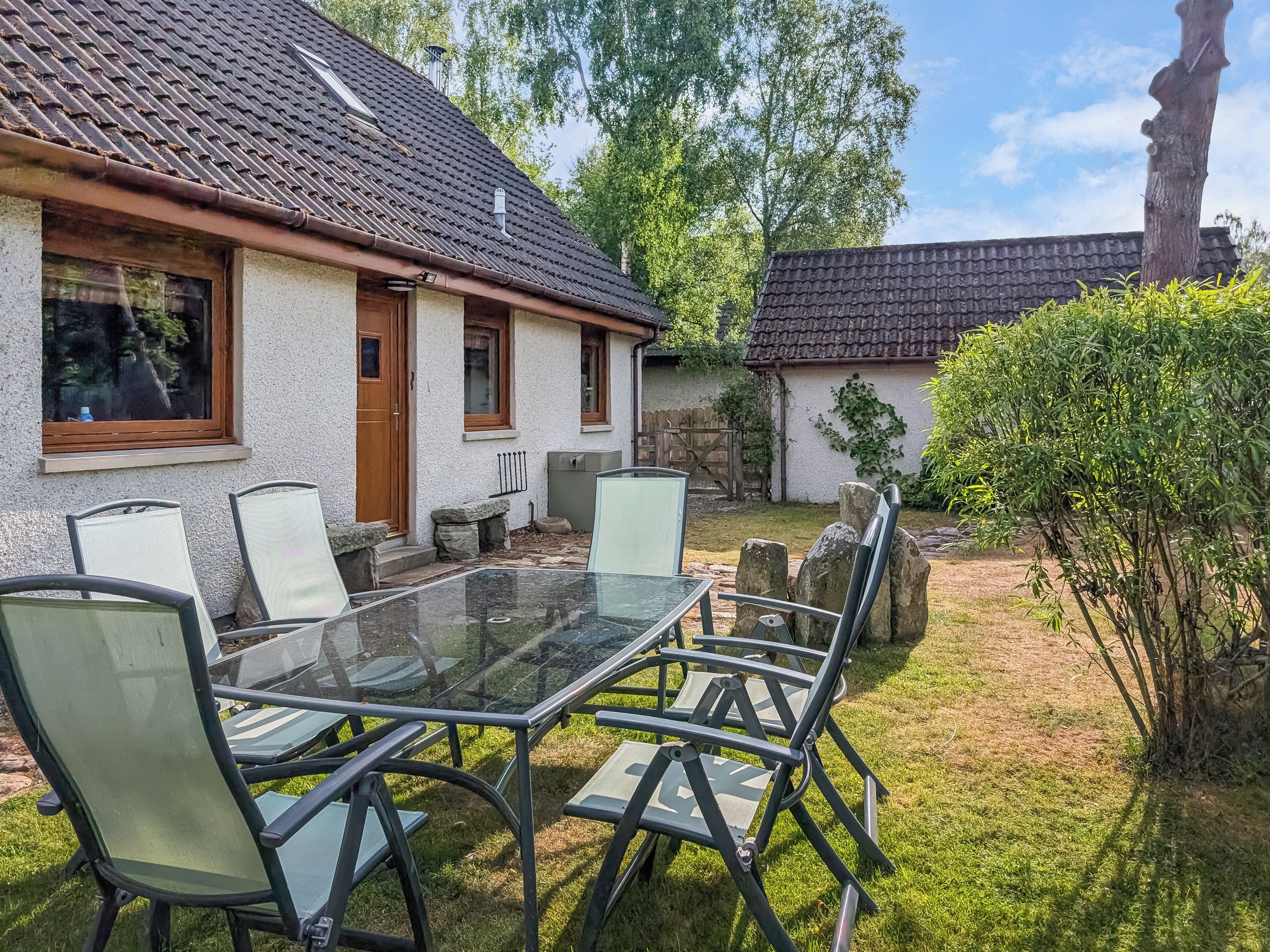 A house with a tiled roof, a glass table, and four chairs.