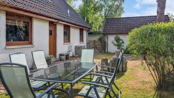 A house with a tiled roof, a glass table, and four chairs.