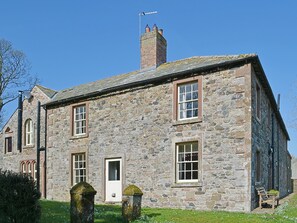 A stone building with multiple windows, a chimney, and a door.