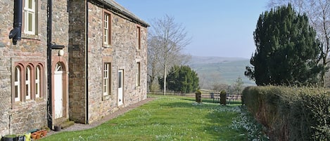 A stone building with arched windows and a grassy yard.