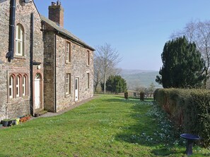 A stone building with arched windows and a grassy yard.