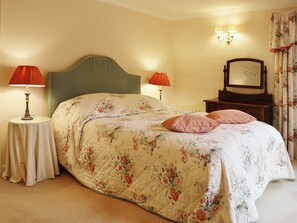 A bedroom with a bed, two bedside lamps, a nightstand, a dresser, and a mirror.