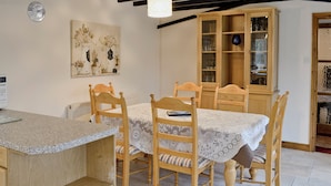 A dining area with a wooden table, chairs, and a cabinet with glass doors.