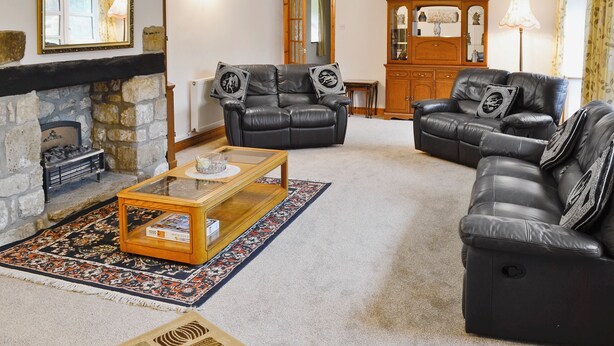 A living room with a fireplace, leather sofas, a coffee table, and a patterned rug.