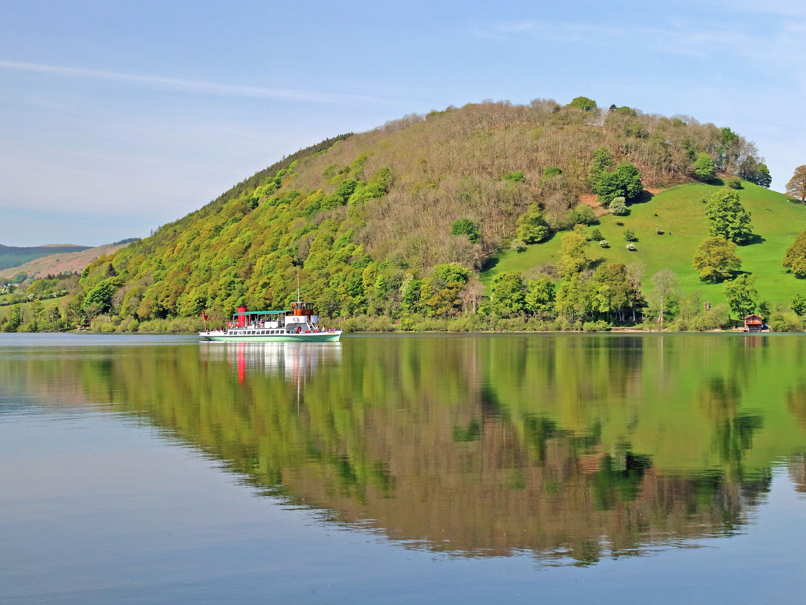 A boat on a calm lake with a hill in the background.