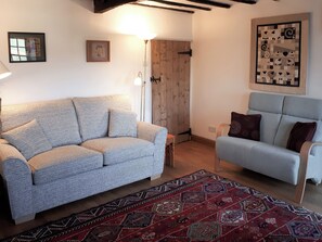 A living room with a sofa, a chair, a patterned rug, and a door.