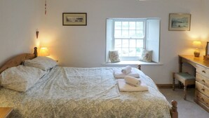 A bedroom with a large bed, a window with a view, a desk with a chair, and two lamps. - 3 bedroom accommodation in Helton (Helton)