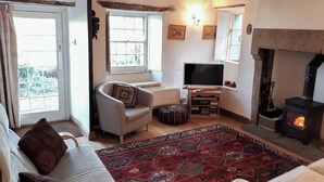 A cozy living room with a fireplace, a television, a sofa, and a patterned rug. - 3 bedroom accommodation in Helton (Helton)