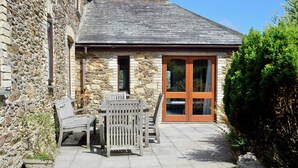 A stone building with a tiled patio, a wooden table and chairs, and a small statue. - 3 bedroom accommodation in Mevagissey, near St. Austell (Mevagissey, near St. Austell)