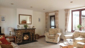 A cozy living room with a stone fireplace, comfortable armchairs, and a television. - 3 bedroom accommodation in Mevagissey, near St. Austell (Mevagissey, near St. Austell)