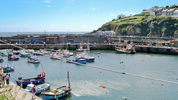 A harbor with various boats docked, a stone wall, and buildings on a hillside in the background. - 3 bedroom accommodation in Mevagissey, near St. Austell (Mevagissey, near St. Austell)