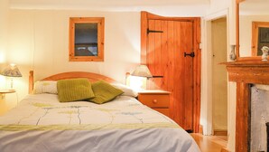 Een slaapkamer met een houten bed, een nachtkastje met een lamp, een houten kledingkast en een spiegel.