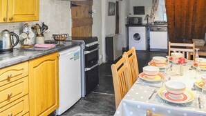 Een compacte keuken met houten kastjes, een fornuis, een magnetron en een wasmachine.
