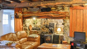 Een gezellige woonkamer met leren banken, een houten salontafel, een stenen muur en een houtkachel.