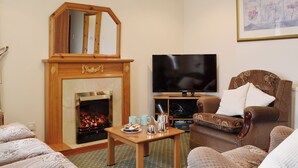 Una sala de estar con chimenea, televisor y un espacio de descanso confortable.