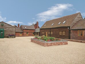 A traditional wooden building with a gravel courtyard and flower beds.