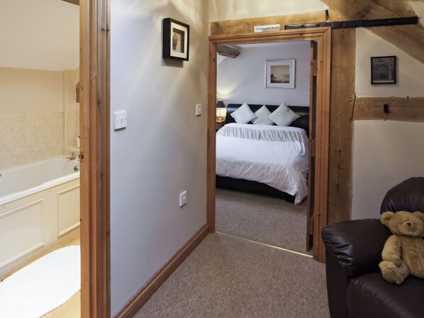 A bedroom with a bed, a teddy bear, a headboard, and a framed picture on the wall.