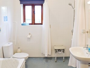 A bathroom with a toilet, a small step stool, a shower, and a sink.