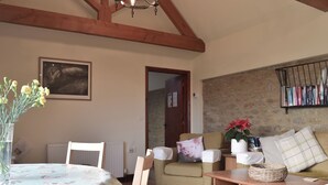 A cozy living room with a dining table, a sofa, and a bookshelf. - 2 bedroom accommodation in East Tytherton, Chippenham (East Tytherton, Chippenham)