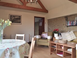 A cozy living room with a dining table, a sofa, and a bookshelf. - 2 bedroom accommodation in East Tytherton, Chippenham (East Tytherton, Chippenham)