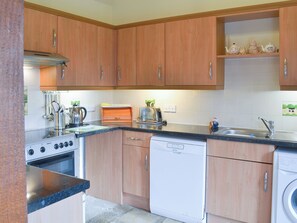 A kitchen with wooden cabinets, a stove, a dishwasher, and a sink.
