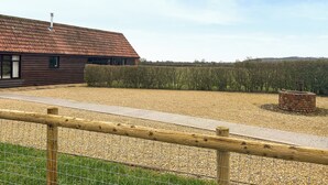 A rustic barn with a sloped roof, surrounded by a gravel path and a hedge. - 2 bedroom accommodation in East Tytherton, Chippenham (East Tytherton, Chippenham)