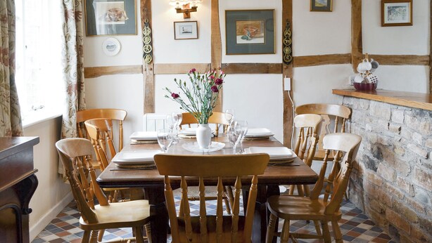A dining area with a wooden table set for six, surrounded by wooden chairs. - 4 bedroom accommodation in Newent, Forest of Dean (Newent, Forest of Dean)