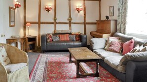 A cozy living room with a fireplace, wooden beams, and a red patterned rug. - 4 bedroom accommodation in Newent, Forest of Dean (Newent, Forest of Dean)