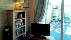 A room with a wooden bookshelf, a television, and a sliding glass door leading to an outdoor area with a table and chairs. - Modern town house only a short distance from the centre of Seahouses. (Seahouses)