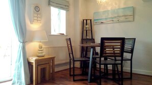A dining area with a wooden table and chairs, a clock on the wall, a window with a view, and a chandelier. - Modern town house only a short distance from the centre of Seahouses. (Seahouses)