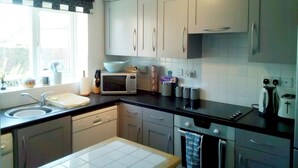 A modern kitchen with white cabinets, a black countertop, and a window providing natural light. - Modern town house only a short distance from the centre of Seahouses. (Seahouses)