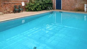 A clear swimming pool with a ladder, surrounded by a brick wall and a door. - 2 bedroom accommodation in Fressingfield (Fressingfield)