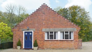 A small brick house with a blue door, a small garden, and a gravel driveway. - 2 bedroom accommodation in Fressingfield (Fressingfield)