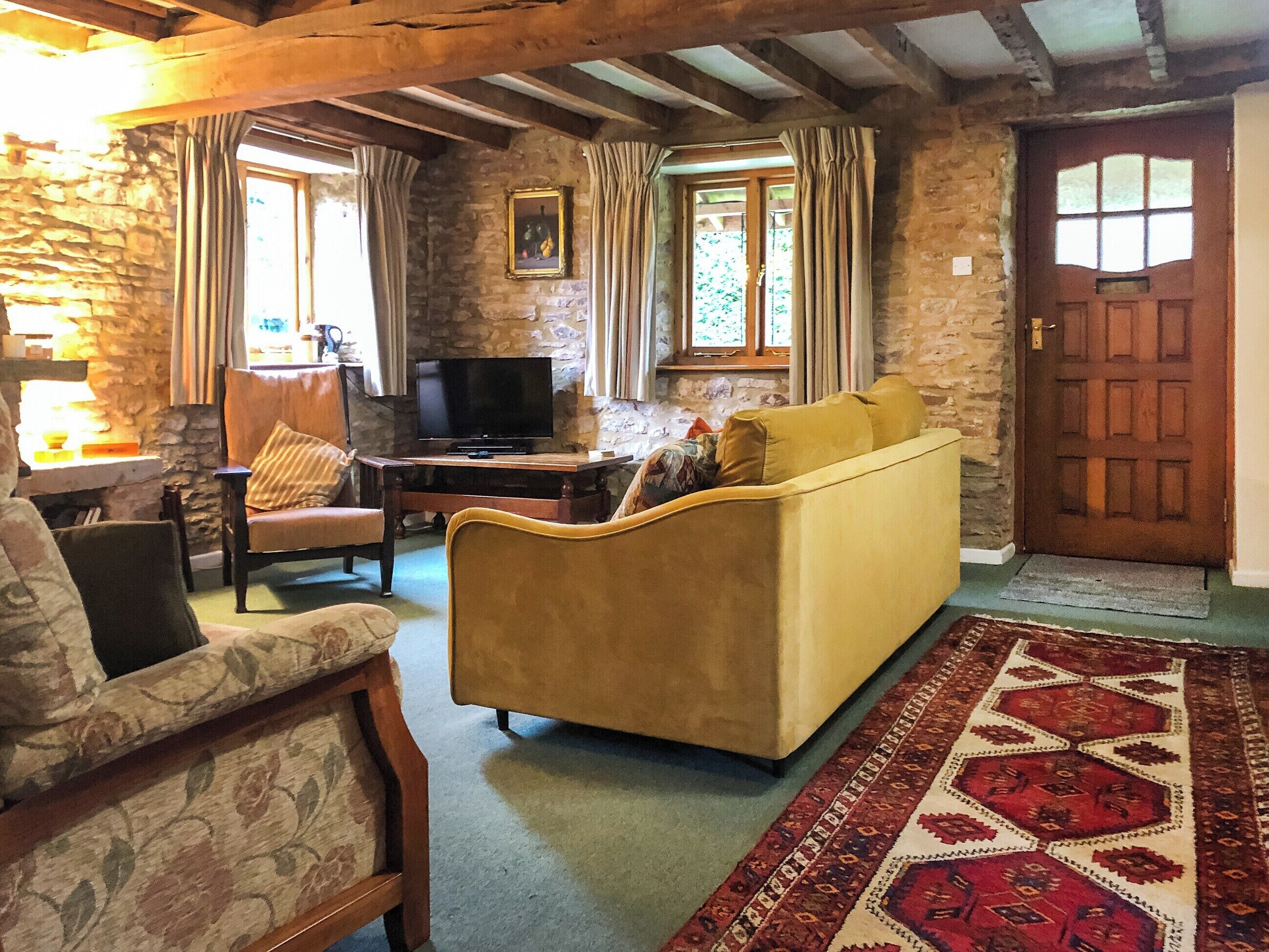 Un accogliente soggiorno con divano, poltrona e televisore su un tavolino in legno.