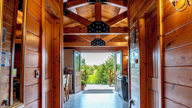 A wooden hallway with a view to an outdoor area, a ceiling with exposed beams, and a door with a sign reading 'BREAD'. - Lake View Lodges - 25076 (Old Leake, near Boston)