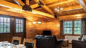 A wooden interior with a sofa, table set for dining, and a television. - Lake View Lodges - 25076 (Old Leake, near Boston)