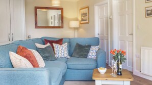 A living room with a blue sofa, a wooden coffee table, and a vase with flowers.
