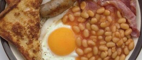 A plate with toast, mushrooms, sausages, bacon, beans, and an egg.
